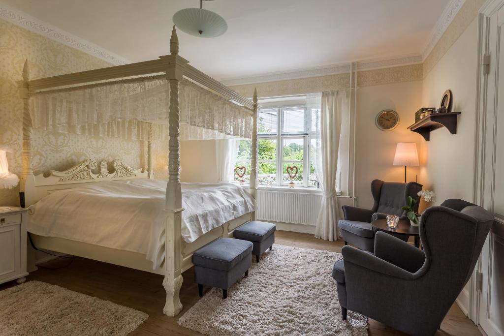 a bedroom with a canopy bed and a chair at Jungshoved Præstegård B&B in Præstø