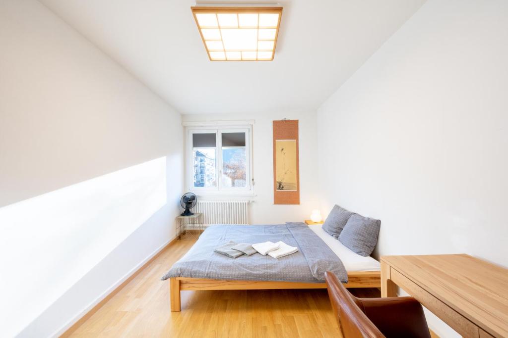 a white room with a bed and a table at Loving apartment right in the heart of Zurich! in Zurich