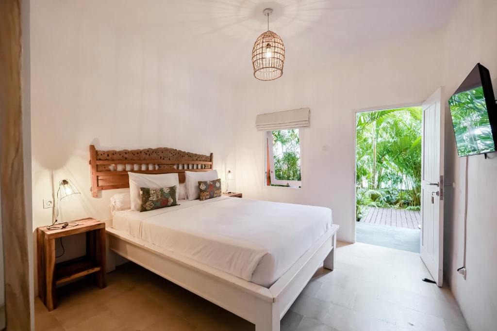 a white bedroom with a large bed and a window at The Room Padang-Padang in Uluwatu