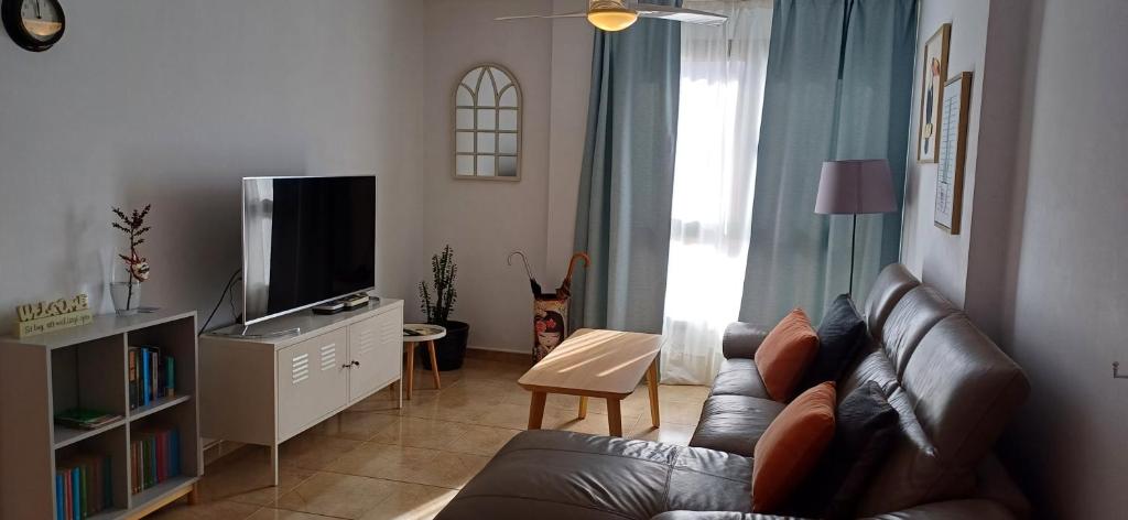ein Wohnzimmer mit einem Sofa und einem TV in der Unterkunft Modern house with 2 bedrooms near the beach in Castillo del Romeral