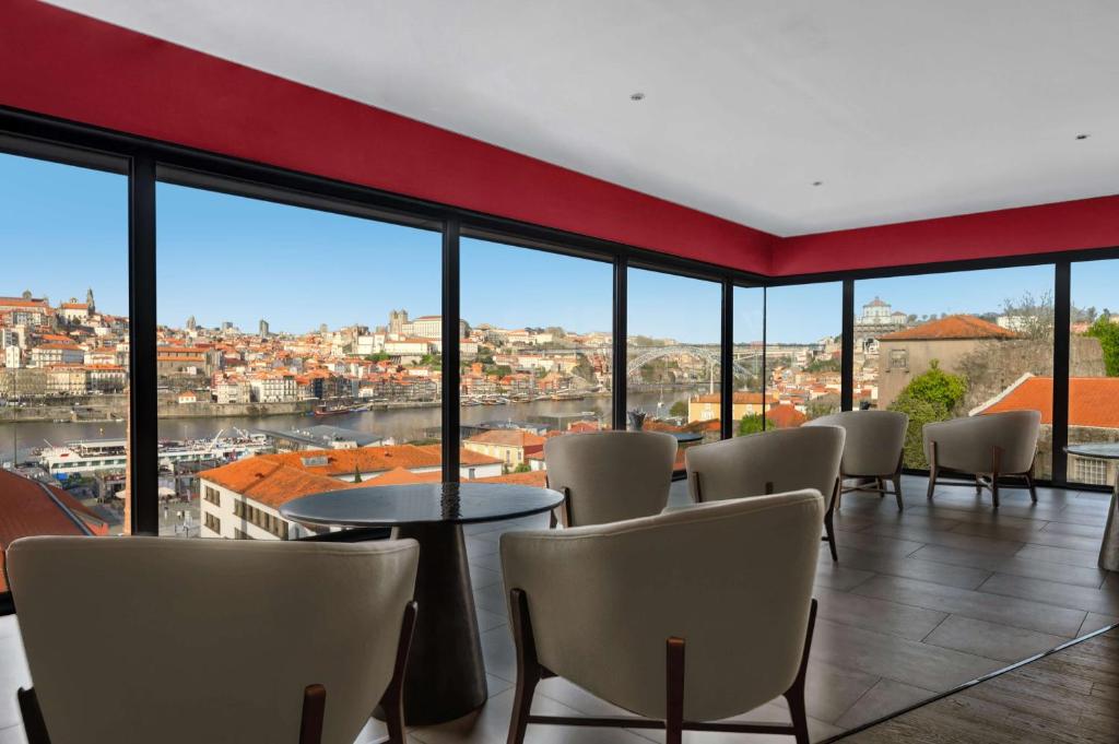 Habitación con sillas, mesas y ventanas grandes. en Hilton Porto Gaia en Vila Nova de Gaia