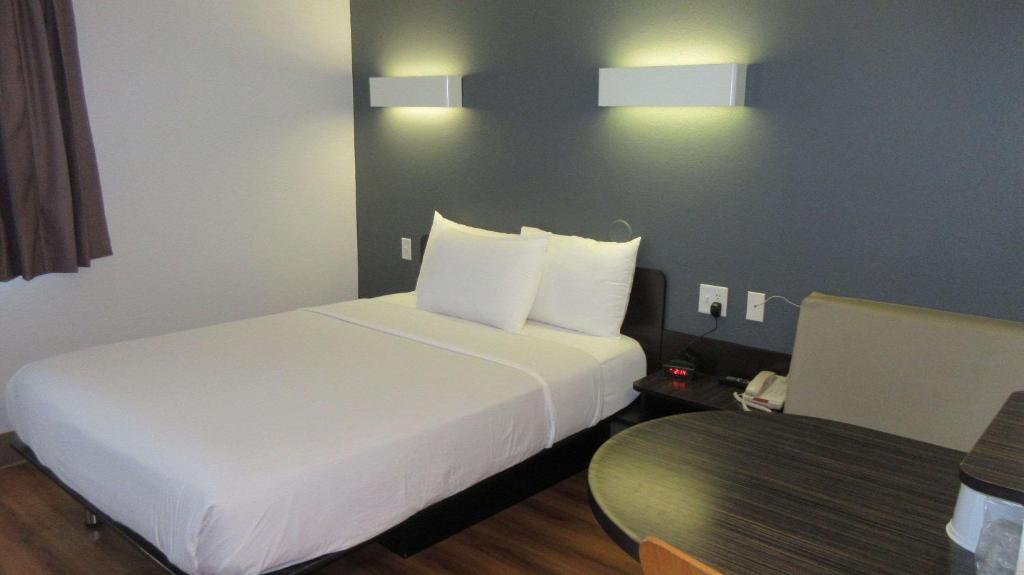 Habitación de hotel con cama blanca y mesa en Econo Lodge, en Idaho Falls