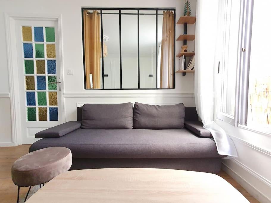 ein Sofa im Wohnzimmer mit Fenster in der Unterkunft Le Surinois T2 Centre in Suresnes