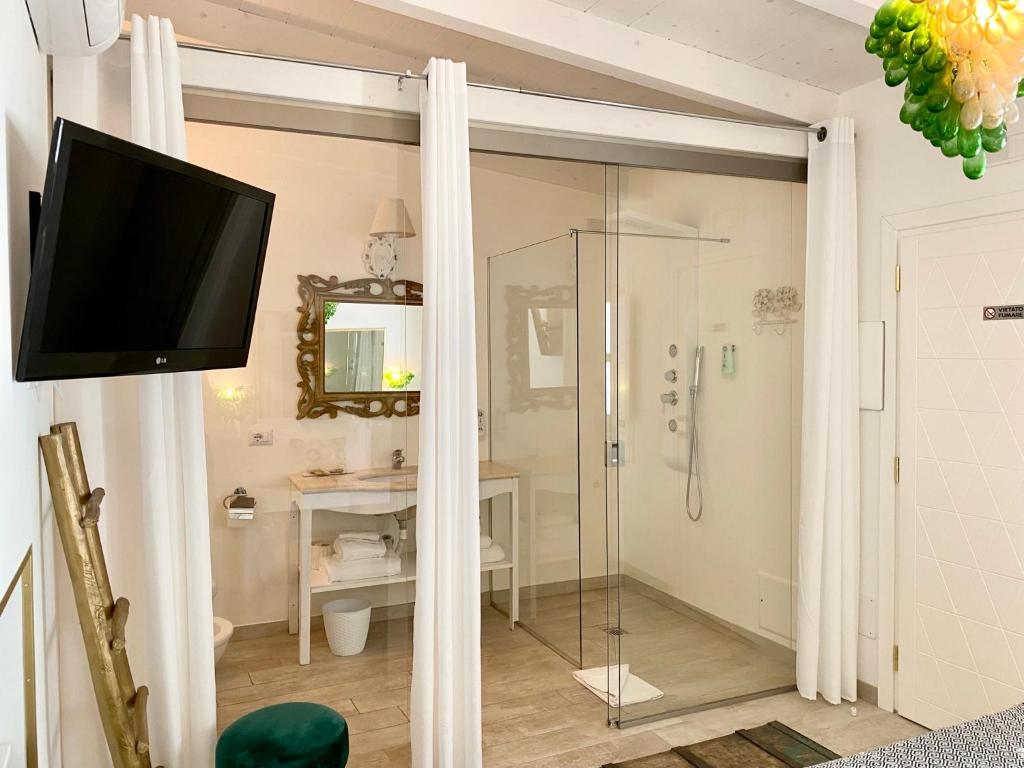 uma casa de banho com chuveiro e uma televisão na parede em In centro unique rooms em Olbia