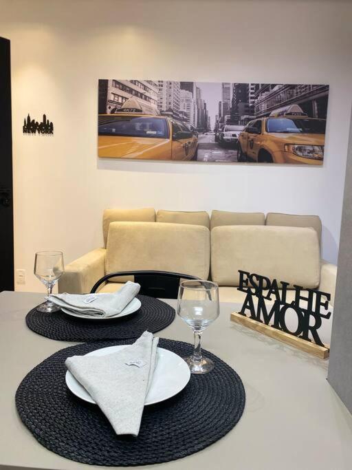 un tavolo con due piatti e bicchieri e un divano di NOVO LOFT inteiro New York, próx. Shop Garten a Joinville