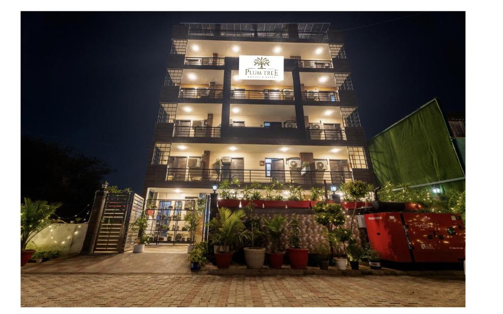 um edifício alto com plantas à frente à noite em Plum Tree Hotels em Gurgaon