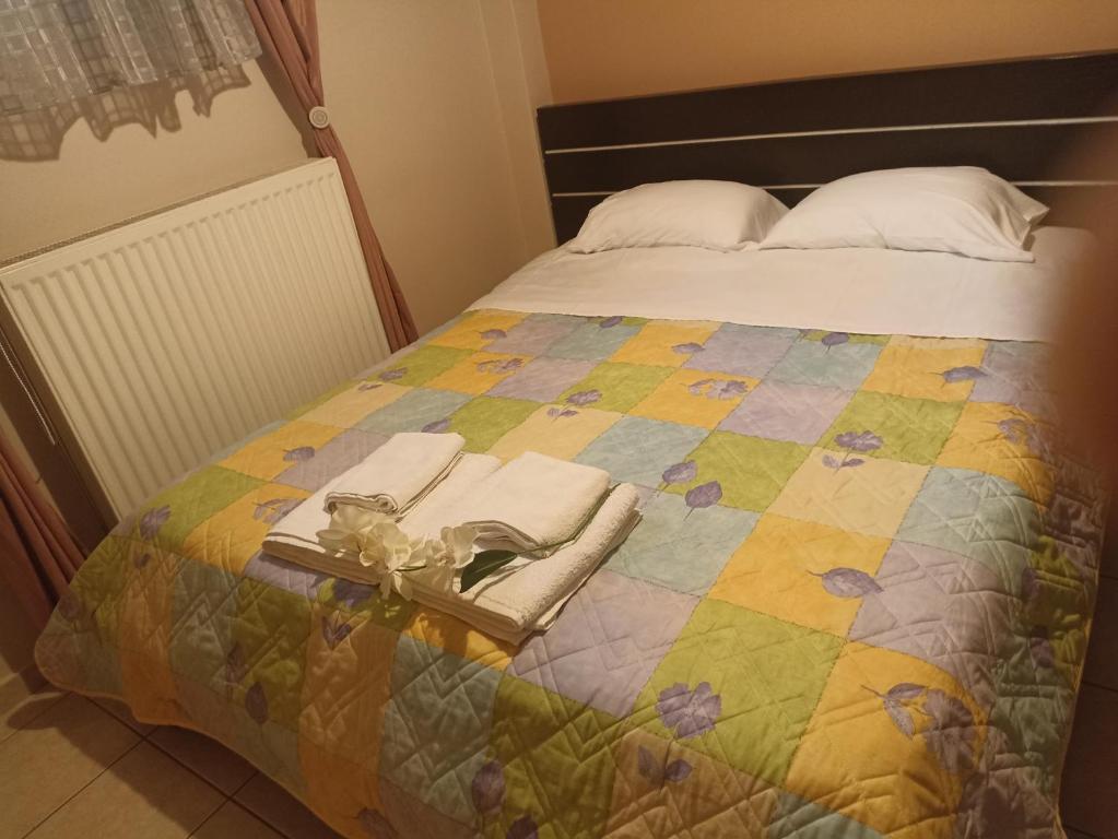 Una cama con un edredón colorido y toallas. en New Village apartment en Chios