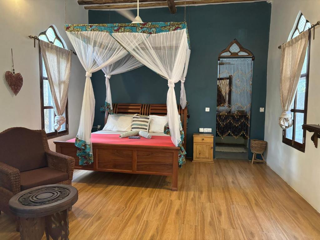 a bedroom with a canopy bed and a chair at Dreamland Bungalows Michamvi Kae in Michamvi