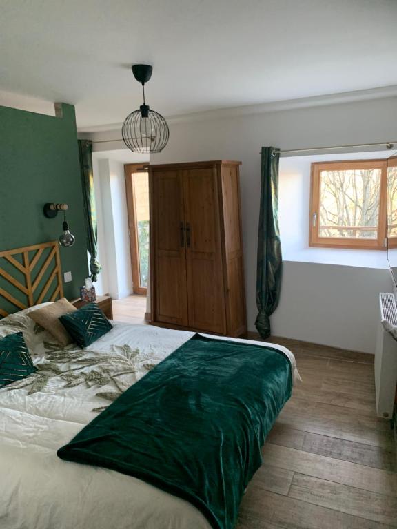 a bedroom with a large bed with a green comforter at Chez Gabriel et Sophie in Pérouges