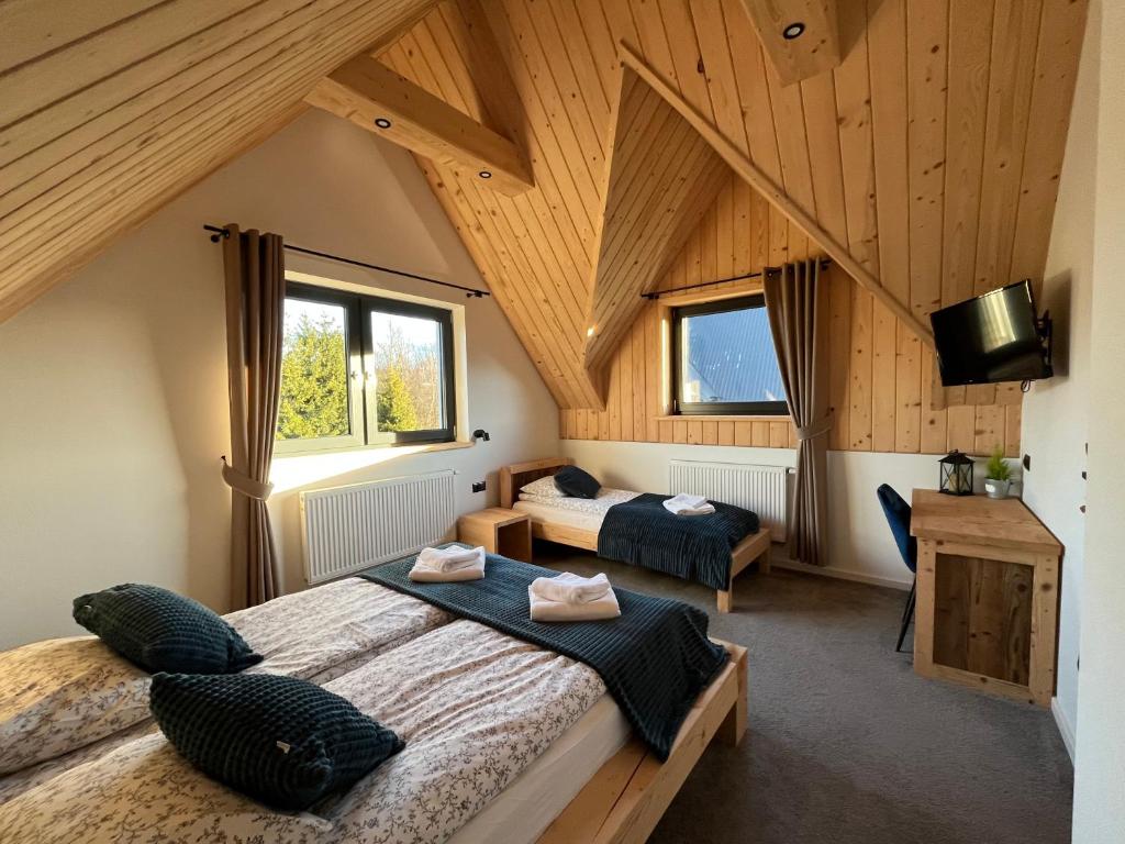 - une chambre avec 2 lits dans une pièce dotée de plafonds en bois dans l'établissement Domek przy Potoku- Szaflary, à Szaflary