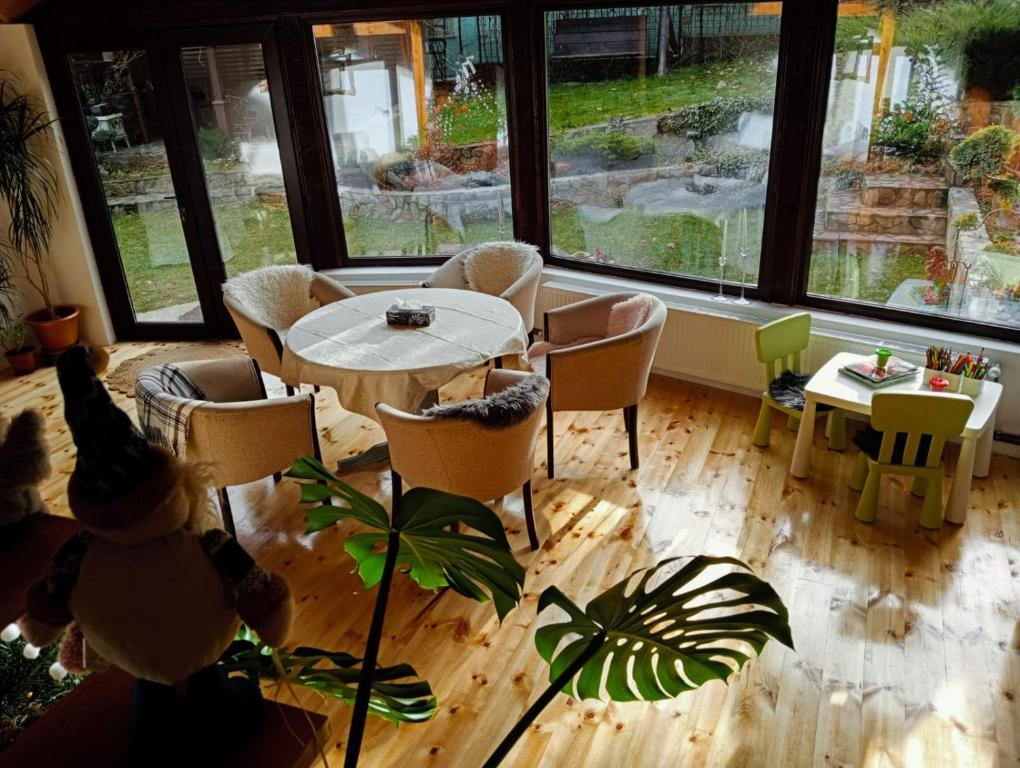 a dining room with a table and chairs and windows at Grădina cu povești in Brezoi