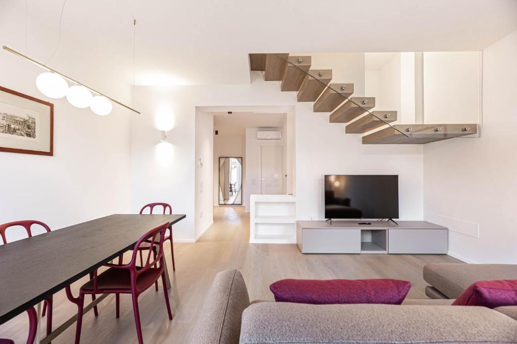 We Home - Romeo&Giulietta Luxury Retreat في فيرونا: غرفة معيشة مع طاولة طعام ودرج