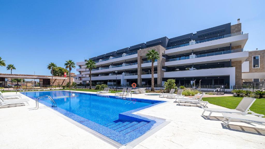 a swimming pool in front of a building at Flamenca Village Penthouse with Private Rooftop and Sea View in Orihuela