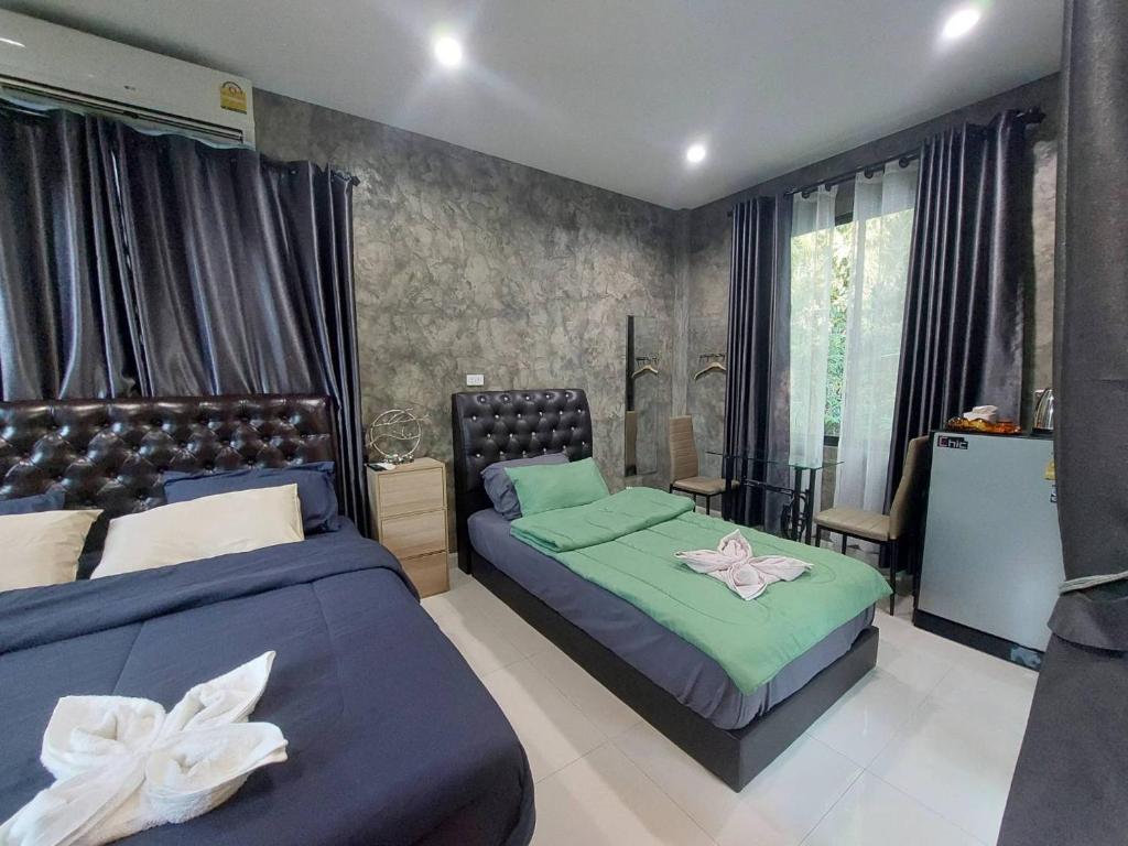 a bedroom with two beds and a table with a chair at Baan Pak Arom Resort Chanthaburi 