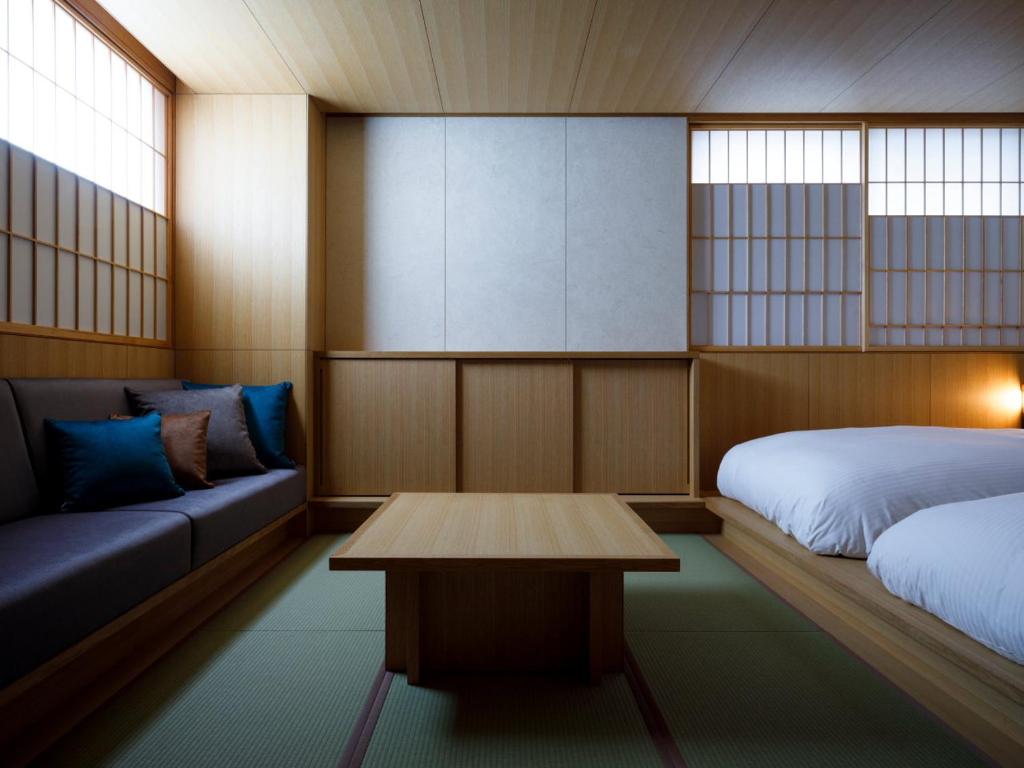 Zimmer mit einem Bett, einem Sofa und einem Tisch in der Unterkunft 黒梅屋 Kurumiya in Kanazawa