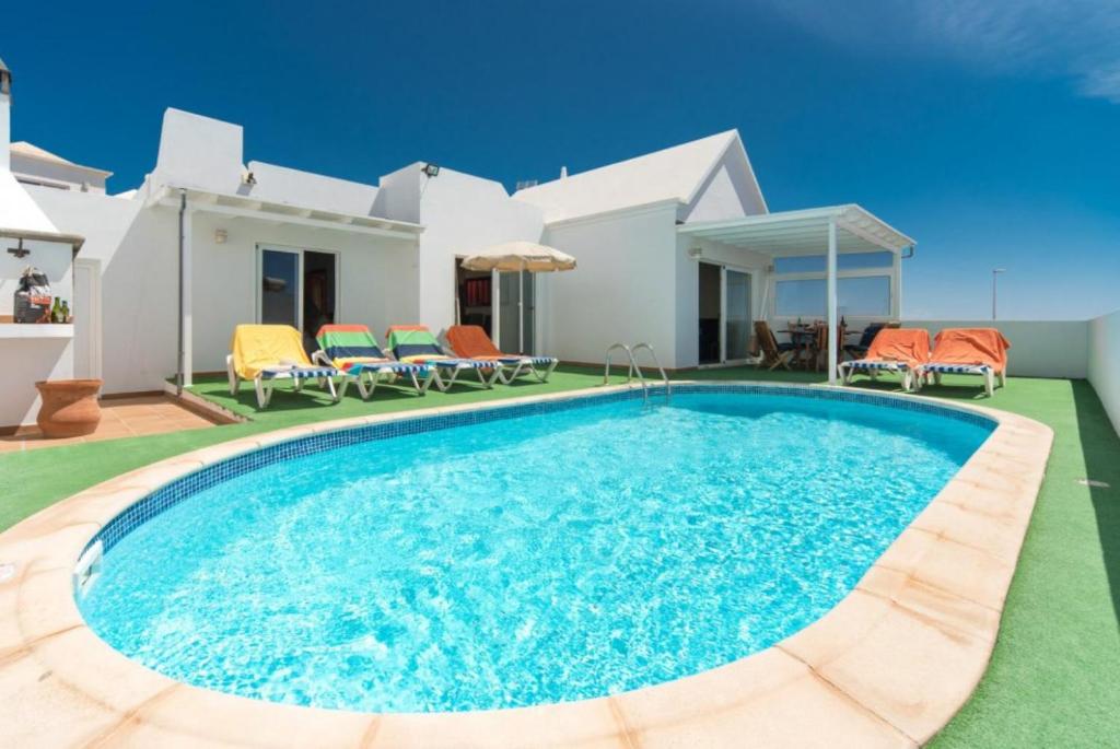 a villa with a swimming pool in front of a house at Villa Reyes in Tías