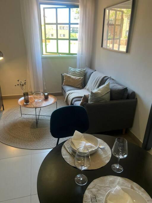 a living room with a couch and tables with wine glasses at Premium Cozy Apartment (0% loadshedding) in Sandton