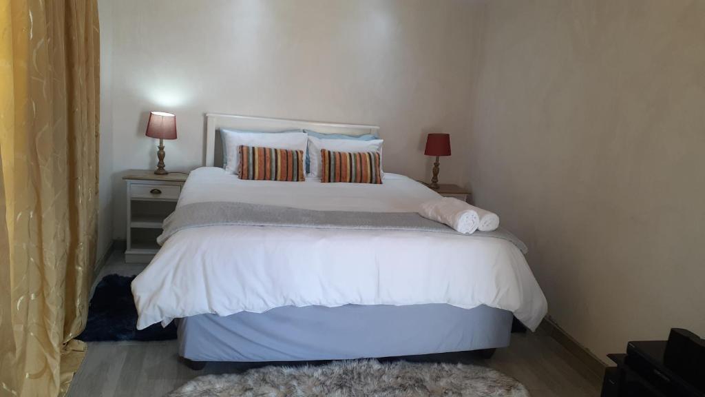 1 dormitorio con 1 cama blanca grande y 2 lámparas en Russell's Rest Rooms en Johannesburgo