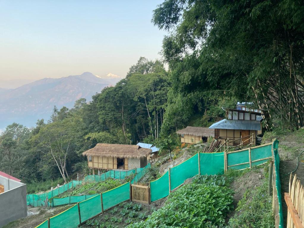 a group of huts on a hill with a green fence at Art Mile Kalimpong in Kalimpong