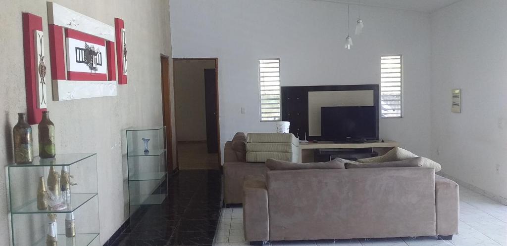 a living room with a couch and a flat screen tv at Chácara Bela Suíça in Itatiba