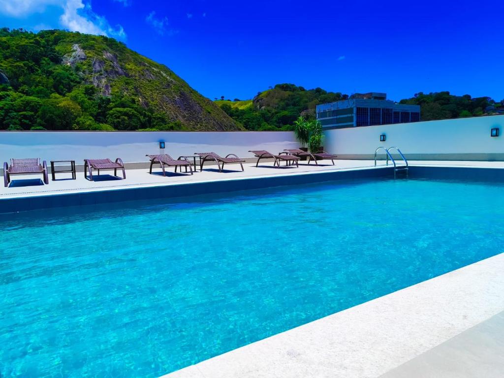 Una piscina con mesas y sillas al lado de un edificio. en Alice Vitoria Hotel Arte by Nobile, en Vitória