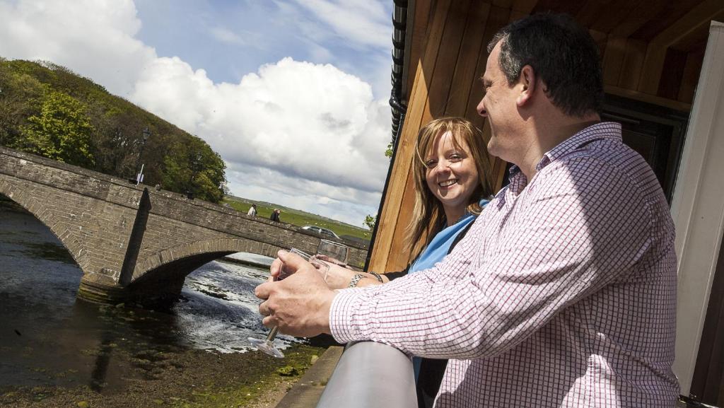 a man and a woman sitting next to a bridge at Riverside Apartments in Wick