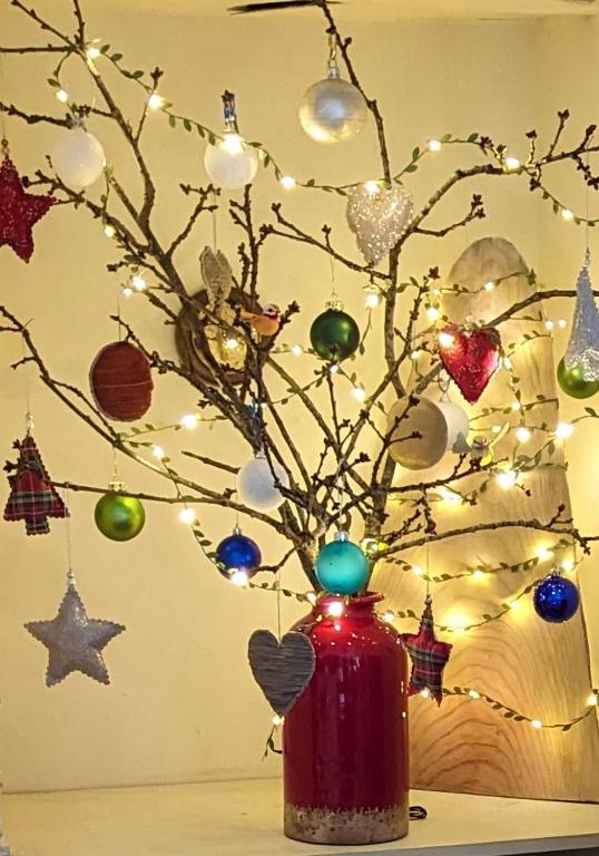 un vase rouge avec des ornements de Noël sur une table dans l'établissement Breizh home A la Boissière, à Merléac