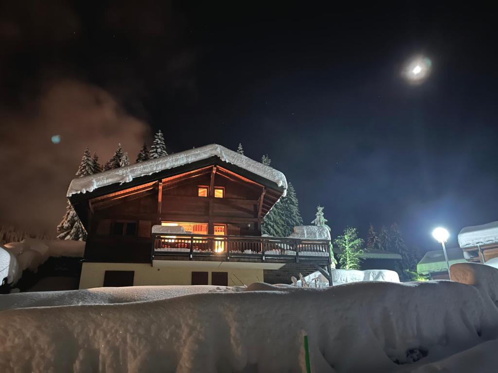 una cabaña de madera en la nieve por la noche en Chalet L'AS DE CARROZ en Arâches-la-Frasse