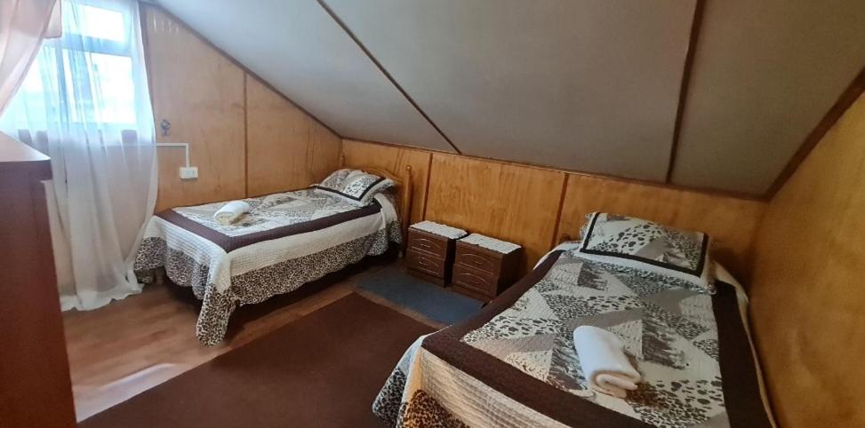 a small room with two beds and a window at Hostal Beagle in Puerto Williams