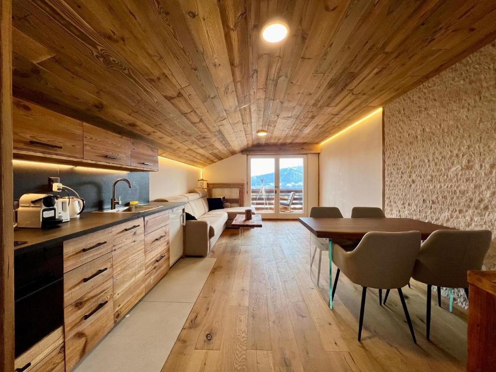 - une cuisine avec un plafond en bois, une table et des chaises dans l'établissement Attique - vue plongeante sur le lac de la Moubra, à Crans-Montana