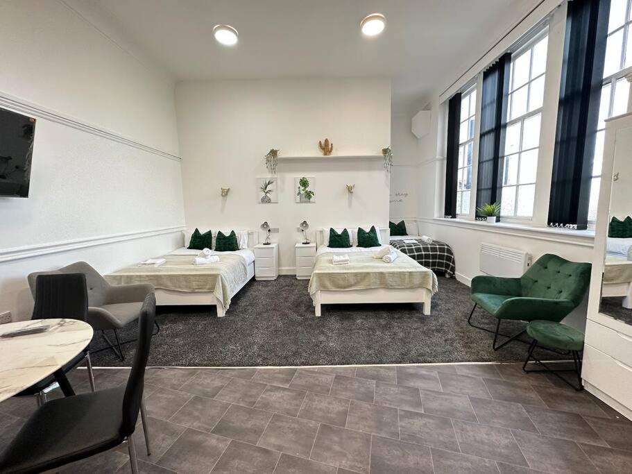 Cette chambre comprend 2 lits, des tables et des chaises. dans l'établissement Modern 3-Bed Haven in West Midlands!, à Birmingham