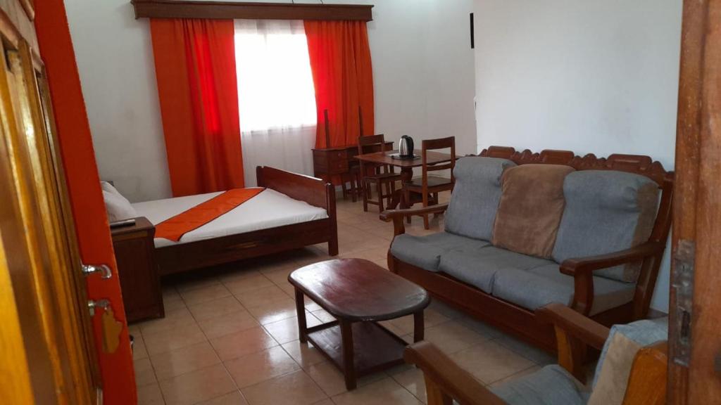 salon z kanapą, łóżkiem i stołem w obiekcie RAOOF HOTEL w mieście Mahajanga