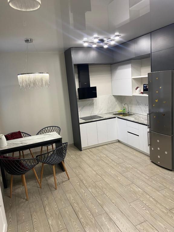 een keuken met witte kasten, een tafel en een koelkast bij VIP apartment у центрі міста, новобудЖК Театральний,дуже простора in Rivne