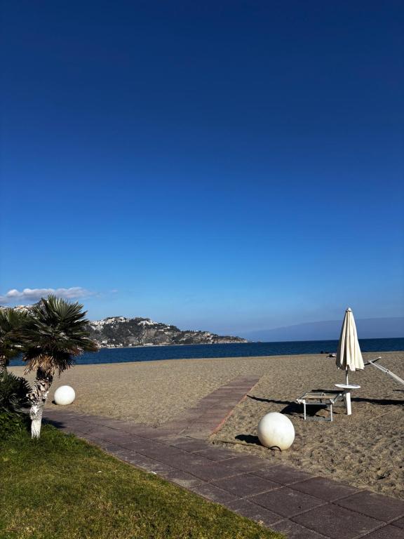 una playa con dos sombrillas y una palmera en Butterflies Home Giardini Naxos, en Schisò