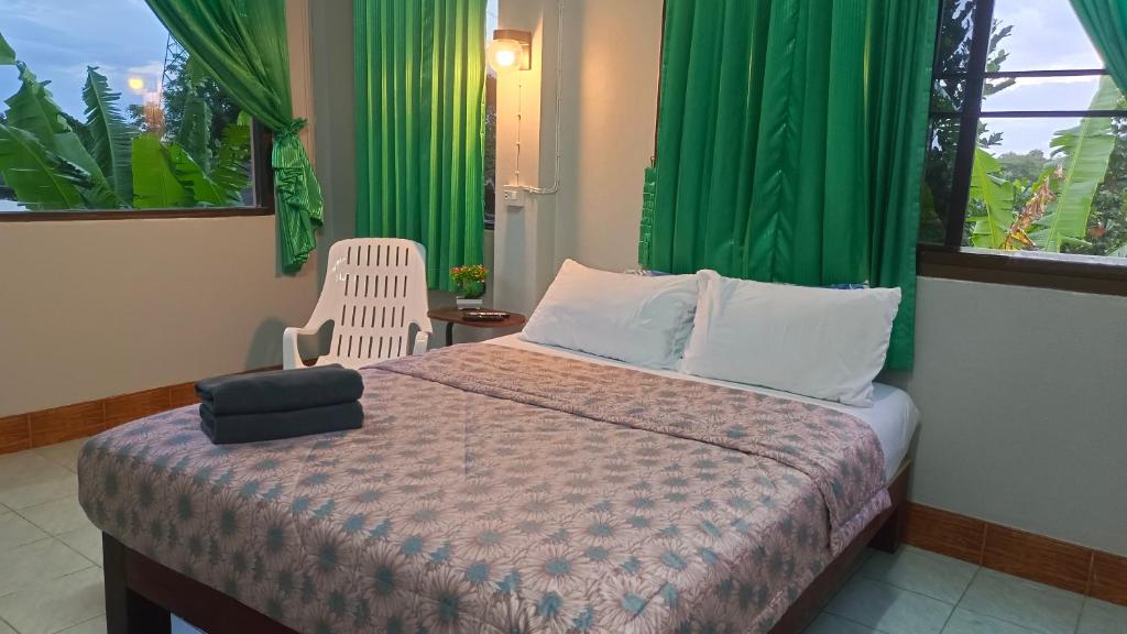 a bedroom with a bed with a chair and green curtains at Mountain View Hostel - Krabi in Krabi