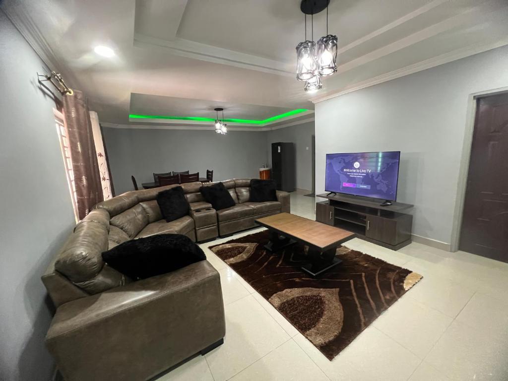 uma sala de estar com um sofá e uma televisão em Lemajy Apartments em Solwezi