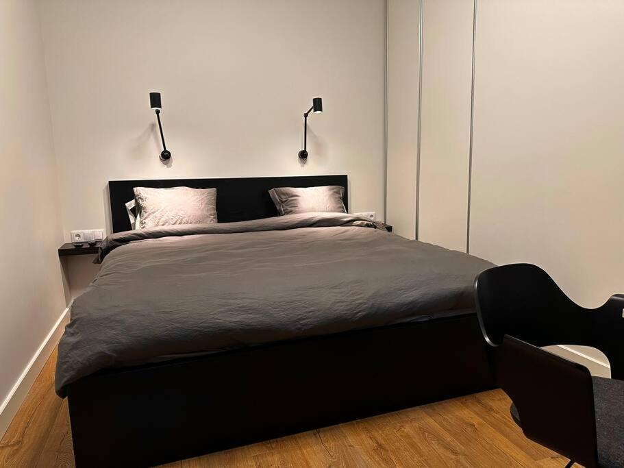 a bedroom with a black bed with two lamps at Stylish studio in the heart of Riga in Rīga