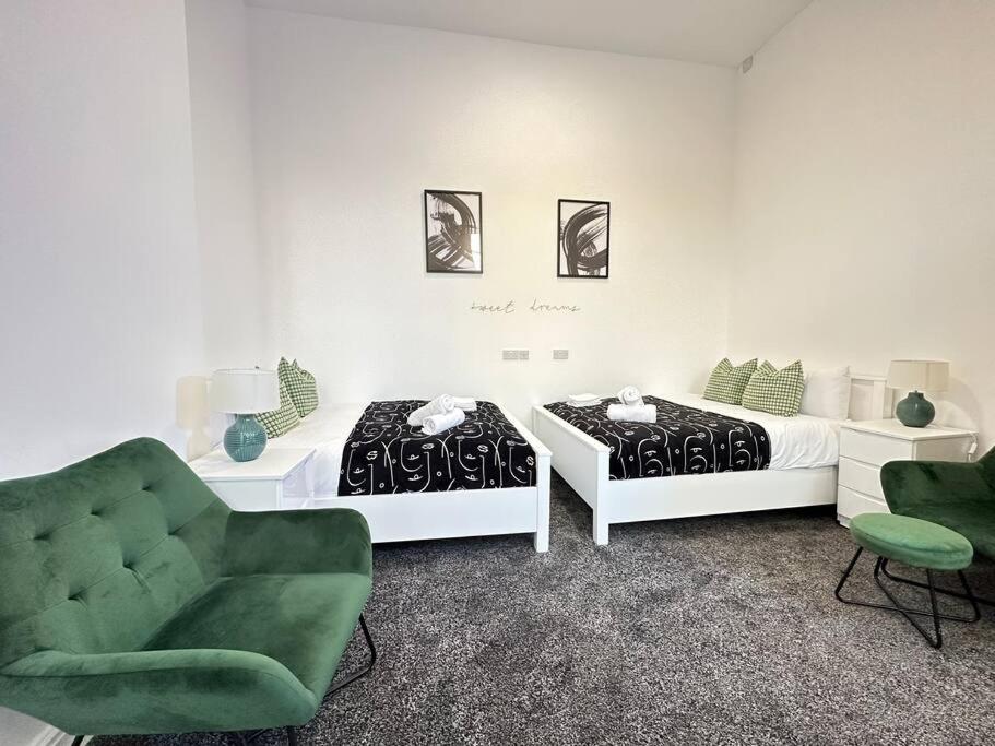a bedroom with two beds and a green chair at Chic Downtown Flat in Dudley Near Attractions in Birmingham