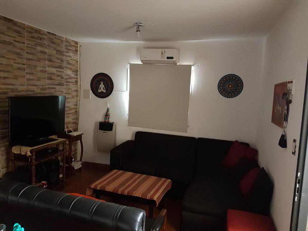 ein Wohnzimmer mit einem schwarzen Sofa und einem TV in der Unterkunft Casa Hogar in Monterrico