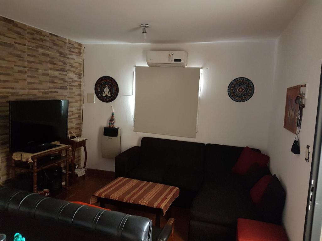 a living room with a black couch and a tv at Casa Hogar in Monterrico