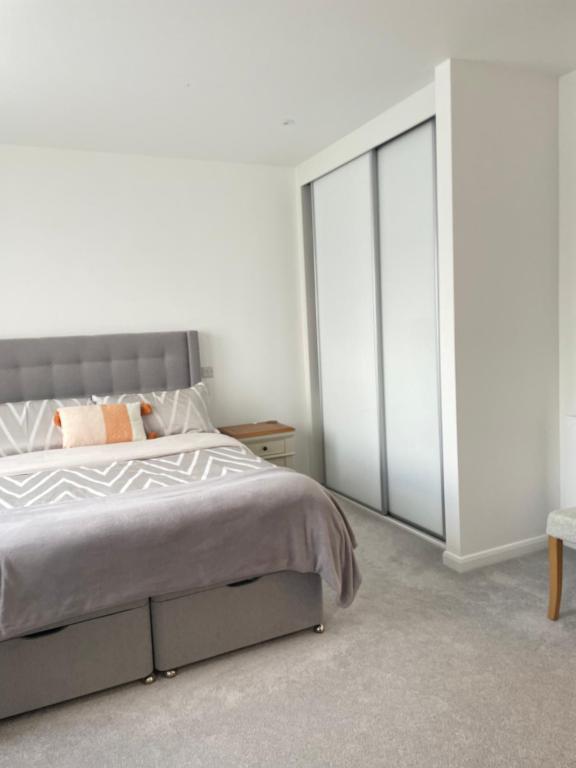 um quarto com uma cama com uma cabeceira cinzenta em Luxury one bedroom flat in Harrow em Harrow