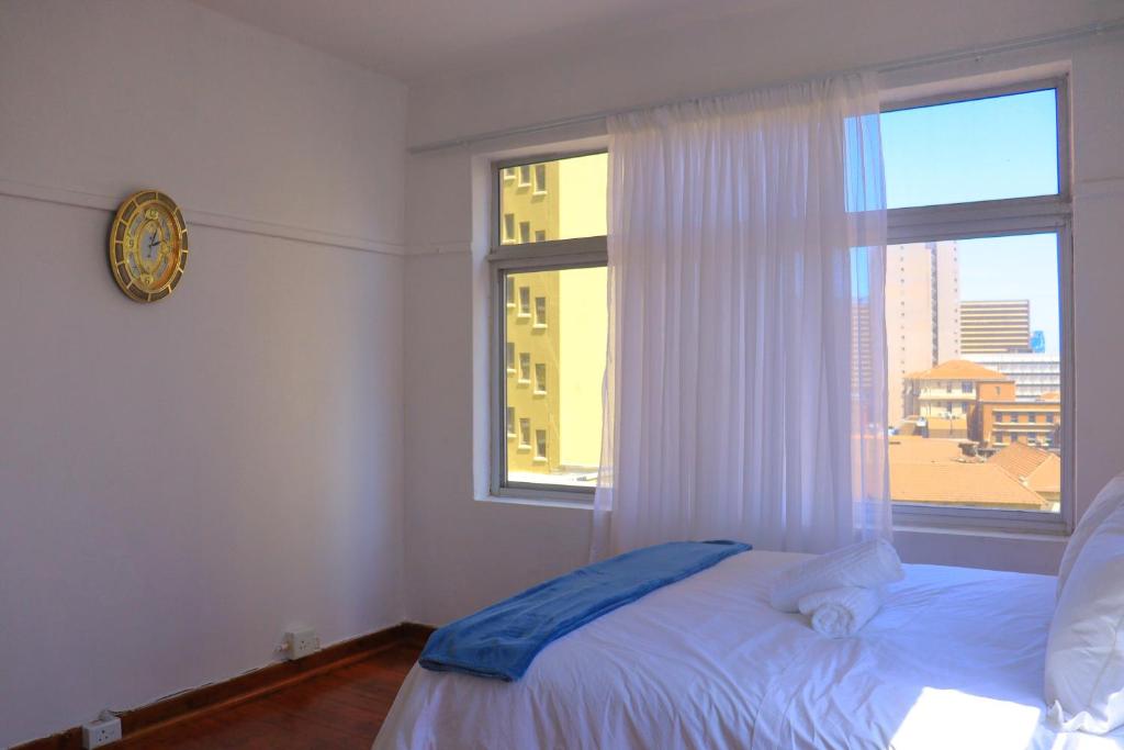 a bedroom with a bed and a window with a clock at Grandborough in Durban