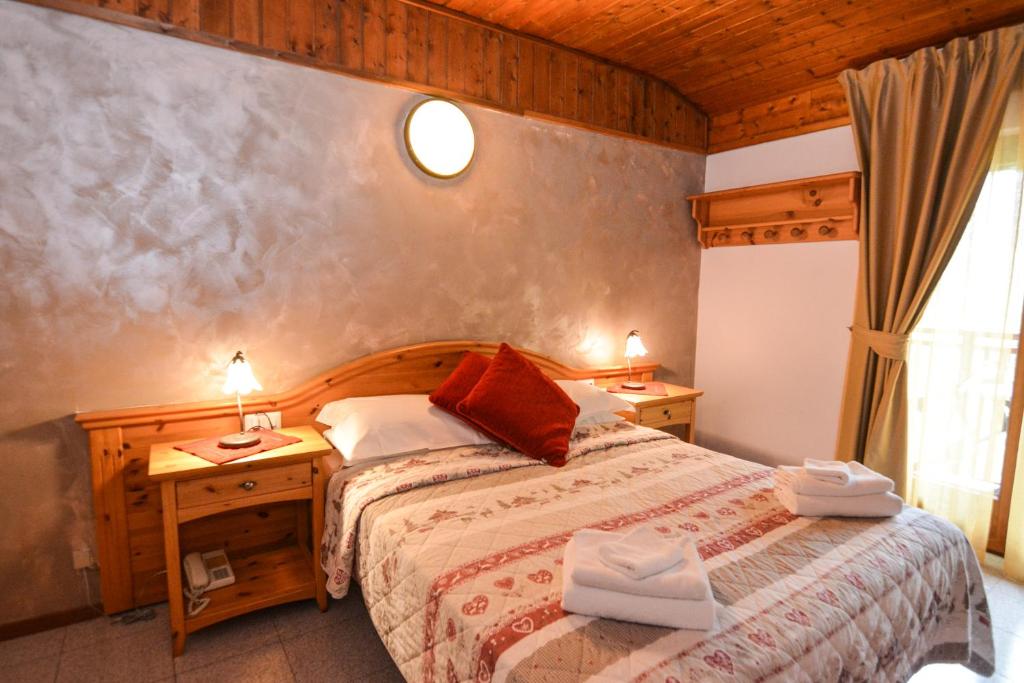 een slaapkamer met een bed en twee nachtkastjes met twee lampen bij Hotel Cima d'Oro in Ledro