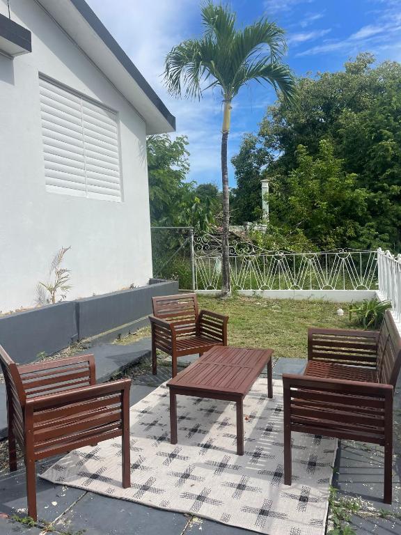 3 bancs en bois assis à côté d'un bâtiment avec un palmier dans l'établissement Casa Escaleras, à Rincon