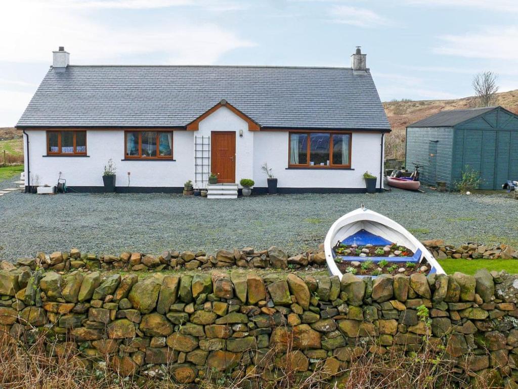 a white house with a stone wall in front of it at Scridain View in Bunessan
