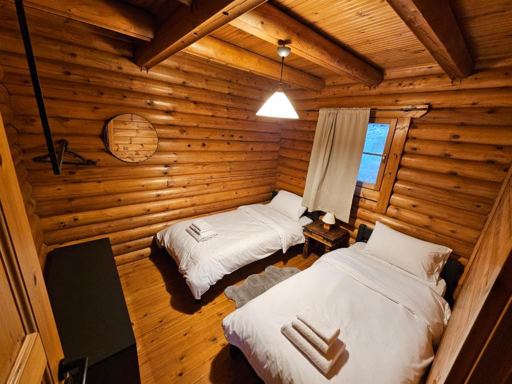 a bedroom with two beds in a log cabin at Orino Livadi Chalet II in Arachova