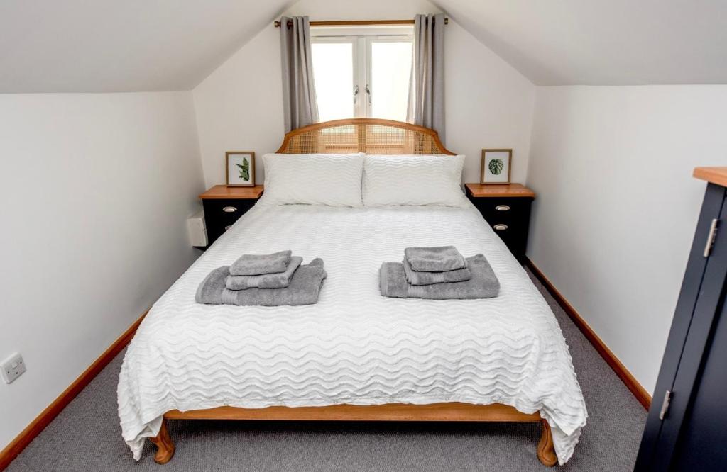 a bedroom with a bed with two towels on it at Woodman's Cottage in Temple Ewell