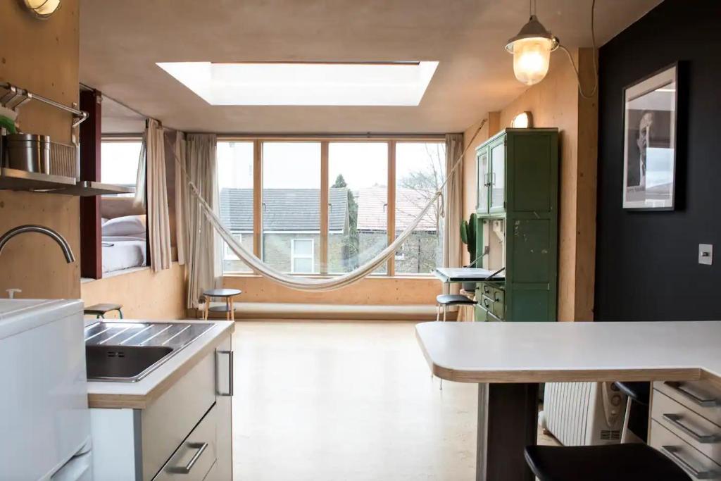 uma cozinha com um lavatório e uma grande janela em Stunning studio loft in Brixton, London em Londres