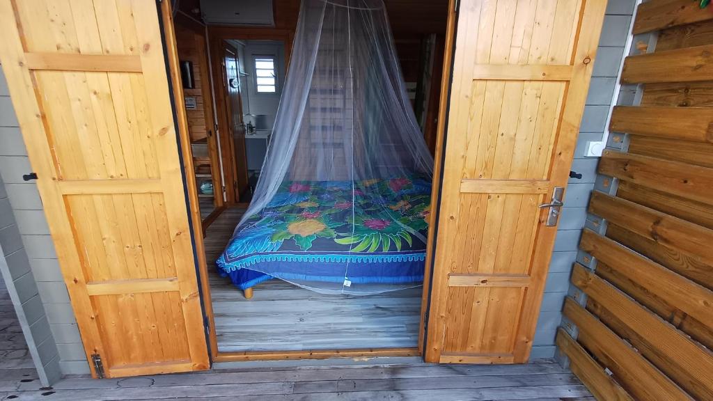 a door to a room with a bed with a net at Bungalows créoles in Saint-François