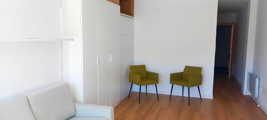 - deux chaises vertes dans une chambre dotée d'un mur blanc dans l'établissement Apartamento en Plaza Central con garaje Gratis, à Sierra Nevada